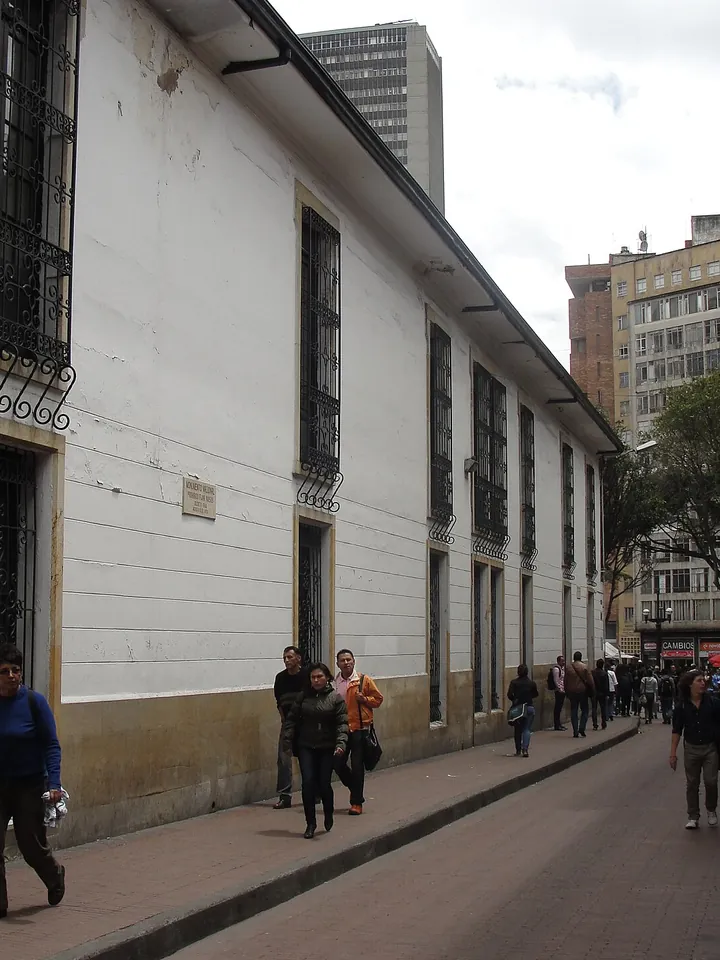 Fachada blanca del Claustro del Rosario, en el centro de Bogotá, con personas caminando por la calle